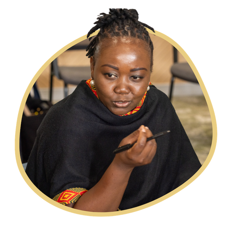 A woman sits talking while holding a pen