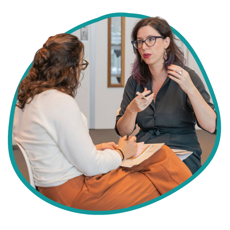 2 women sit together in conversation