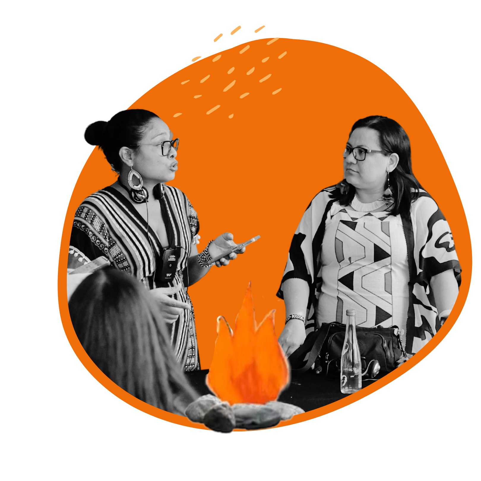 Two women stand talking to each other during a FIRE program behind an illustration of a burning fire