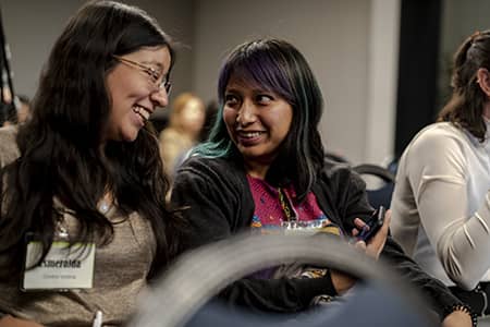 FIRETwo women smiling, looking at each other in complicity during a FIRE program activity