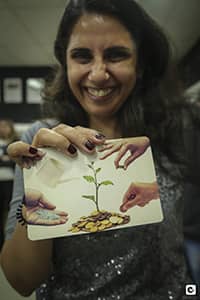 FIRESmiling woman holding a picture in front of the camera as part of a FIRE program activity