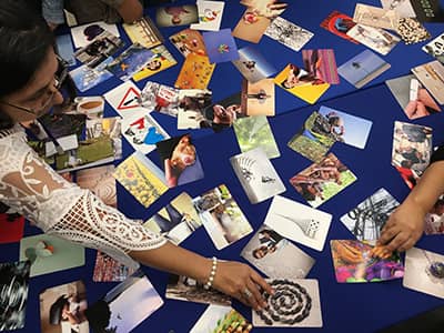 FIREHands of participants taking photographs of a blue round table as part of a dynamic of the FIRE program