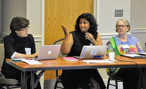 Three women participating in the FIRE program, the one sitting in the middle holding a microphone and sharing her points of view