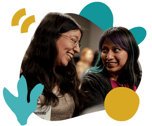 Two program participants sitting next to each other during a training in Mexico look at each other and smile