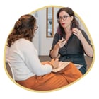 2 women sit together in conversation