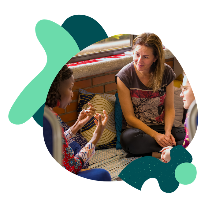 A Spring coach sits in a group of 3 on the floor and listens intently