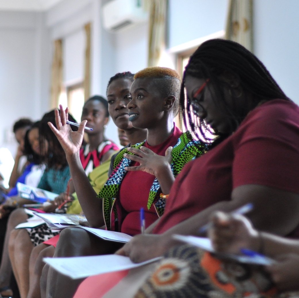 A woman speaks in the middle of a row of her female colleagues during a training