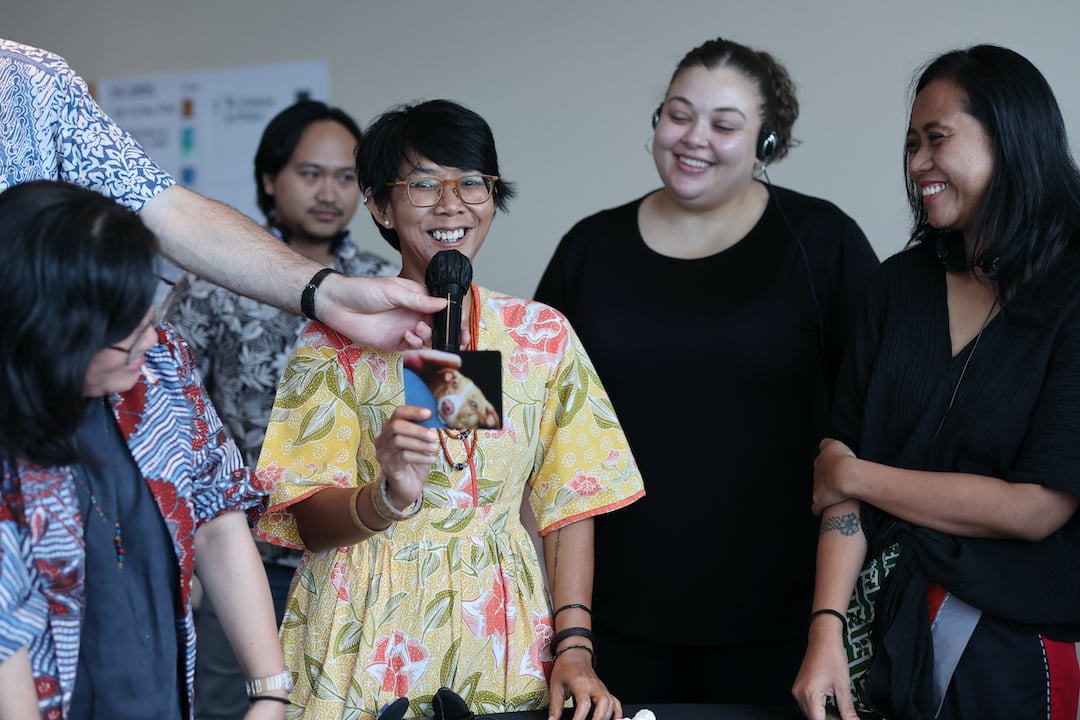 A woman speaks into a microphone holding up a 