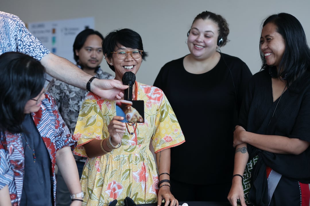 A woman speaking into the microphone as part of a group mechanic in the FIRE in-person program