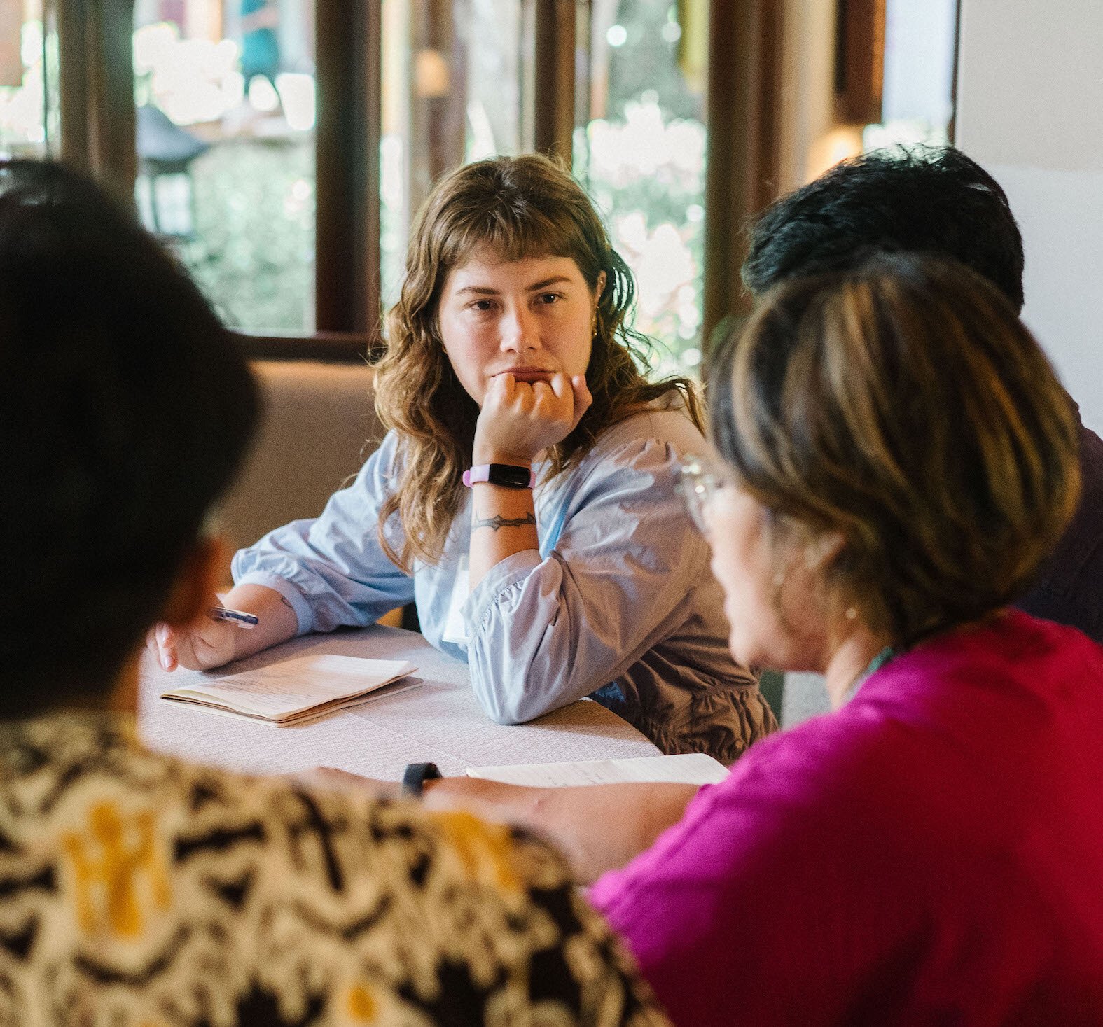 A program participant with her head resting on her hand while listening to someone sitting across from her