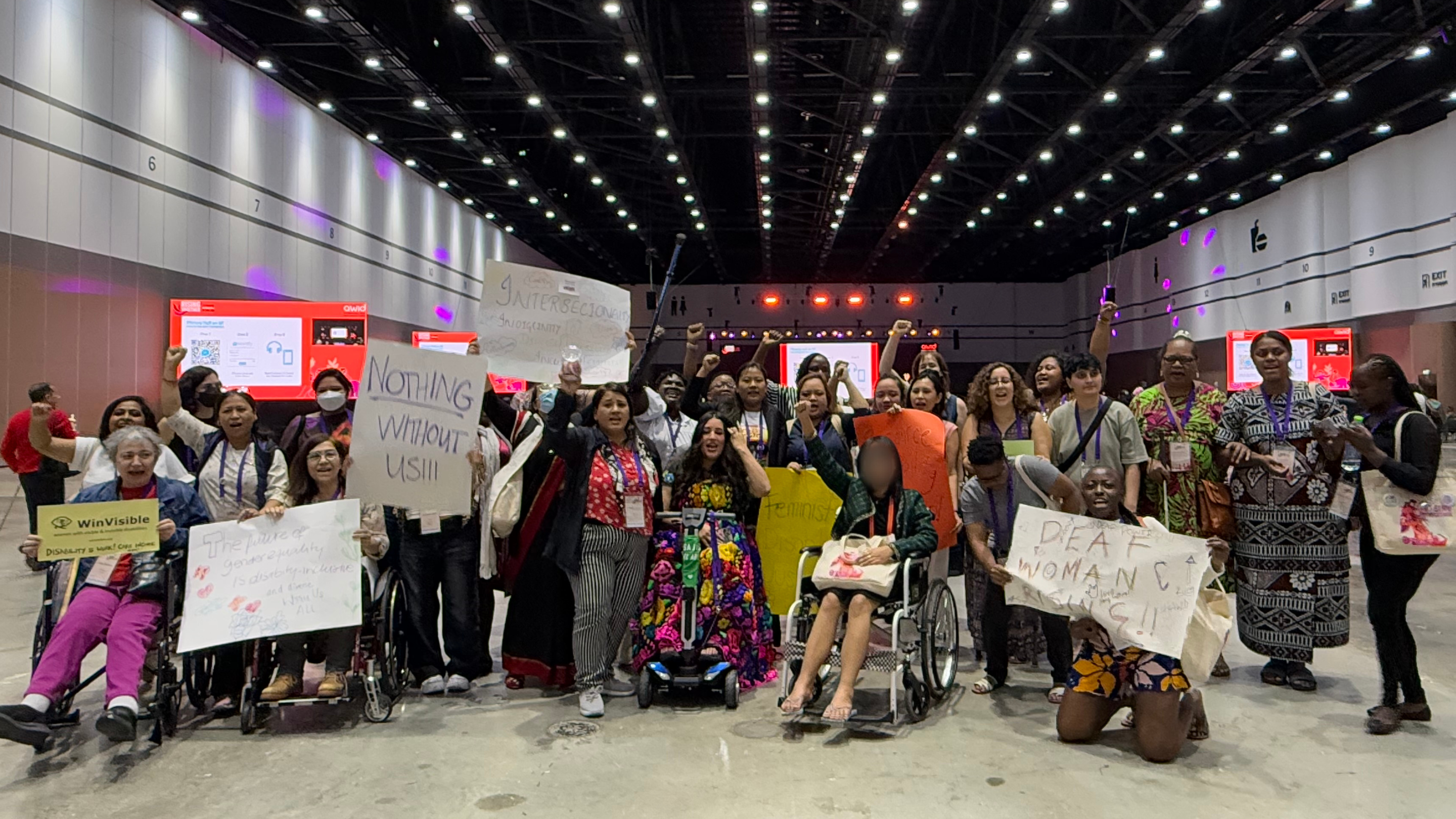 Disability Justice March organized by WEI during the AWID Forum. A group of people pose with signs reading "Nothing without us" "Intersectionality" and more. Credit: WEI.