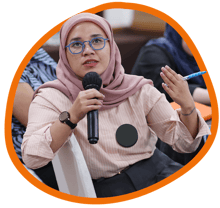 A woman sits and speaks into a microphone
