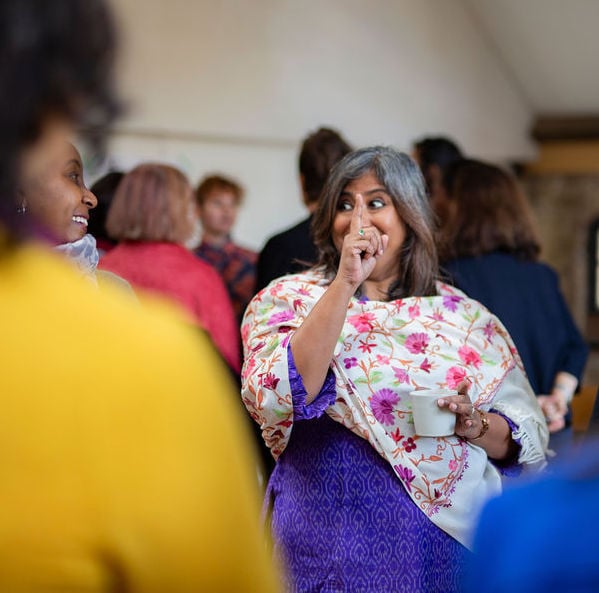 A woman in the middle of a group during a training, pointing her finger upwards as she talks to other participants