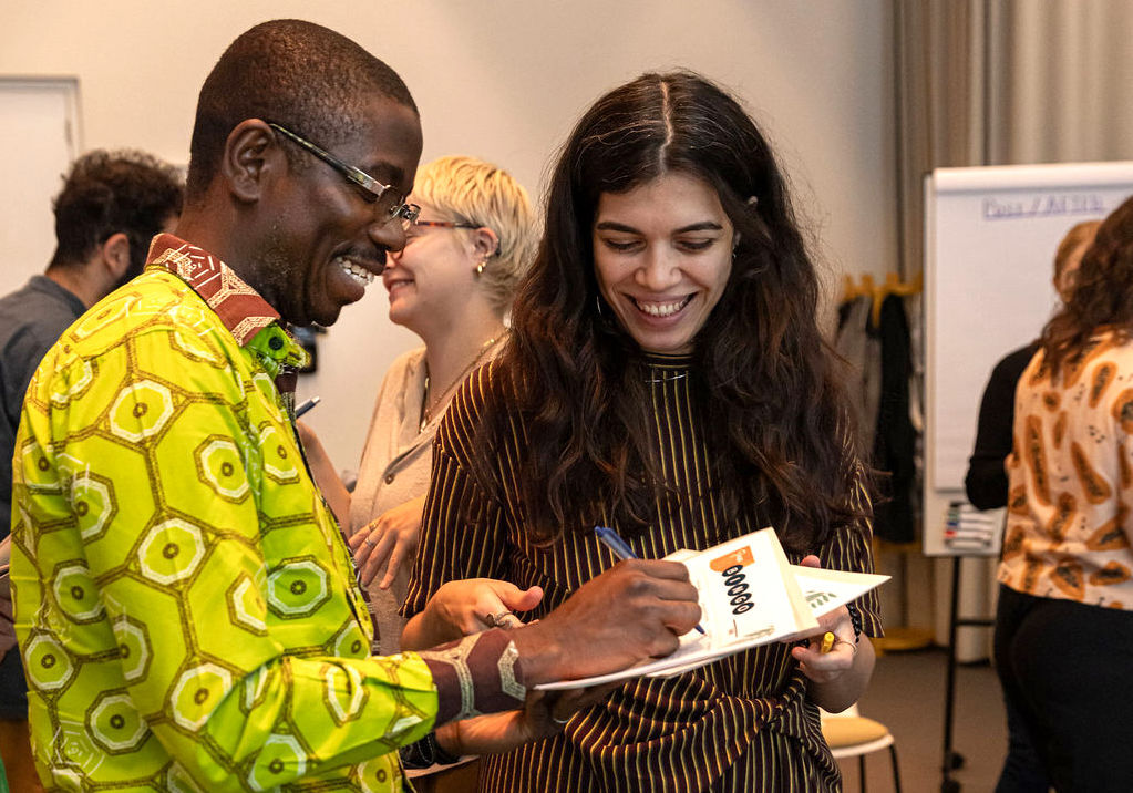 A man and a woman stand next to each other and smile as they write on a paper during a state shift exercise