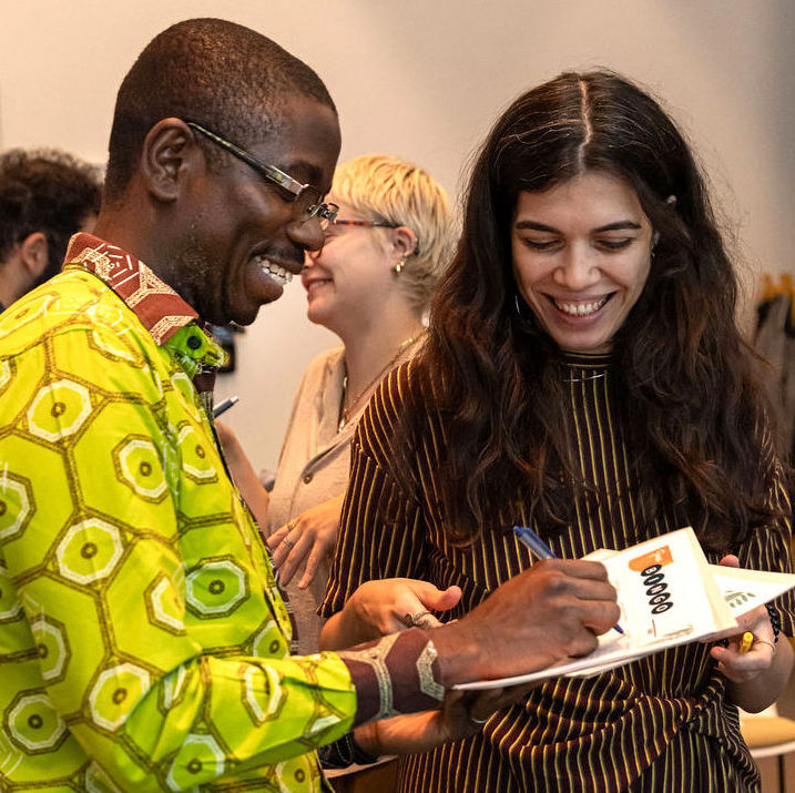 2 people stand together smiling and writing on a paper during a state shift exercise