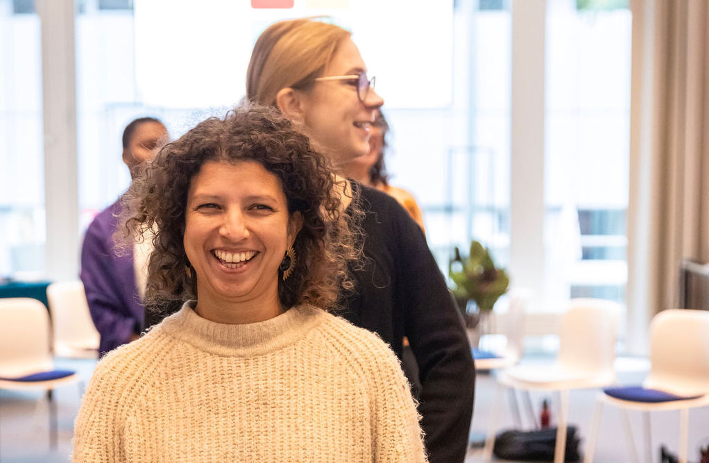 Two women stand in single file with the one at the forefront smiling during a state shift activity