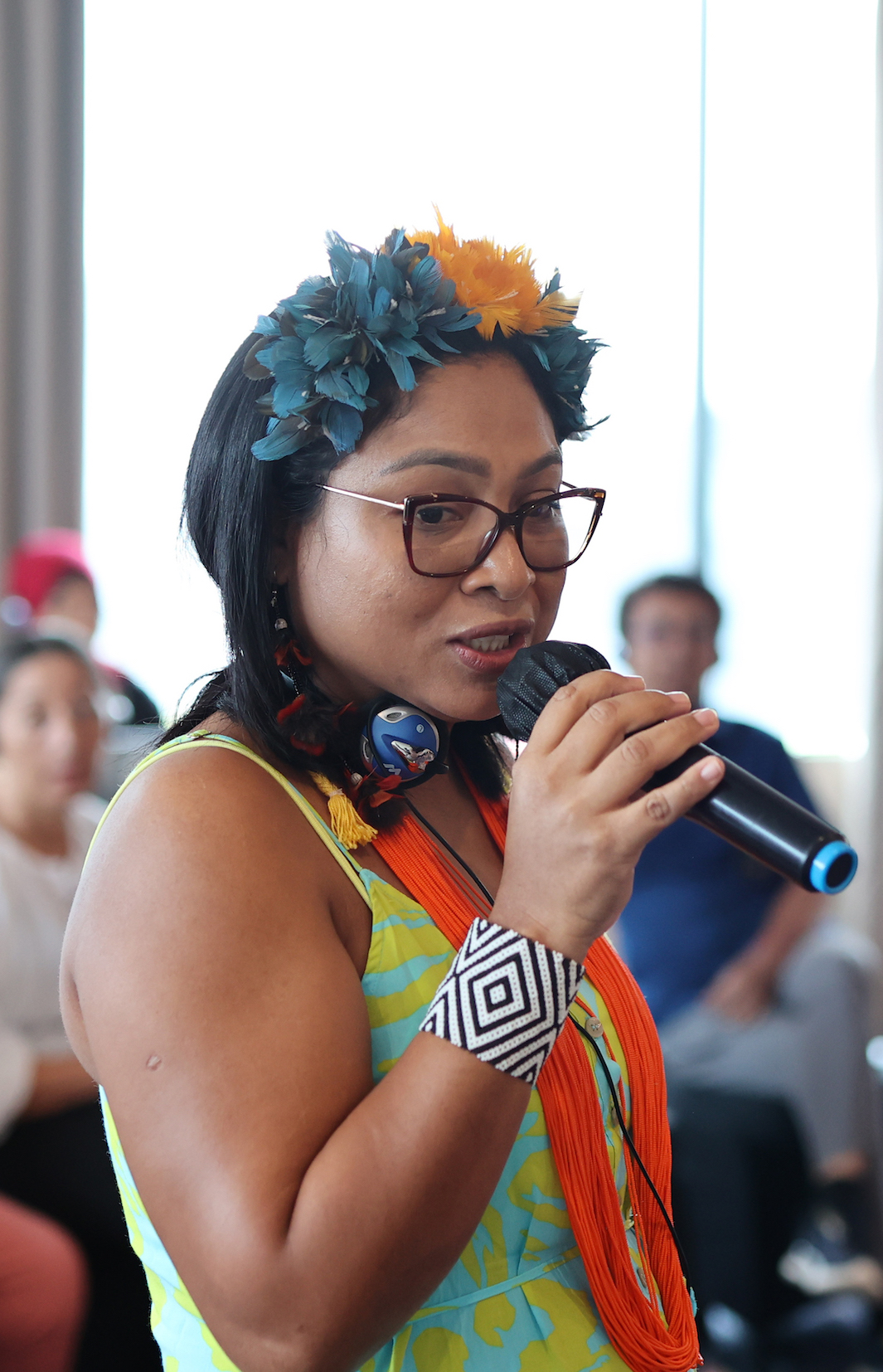 An Indigenous woman talks into a microphone during a global exchange in Jakarta